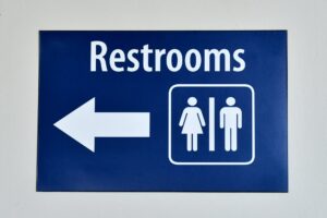 A public restroom sign with a male and female symbol pointing in right direction for facilities.