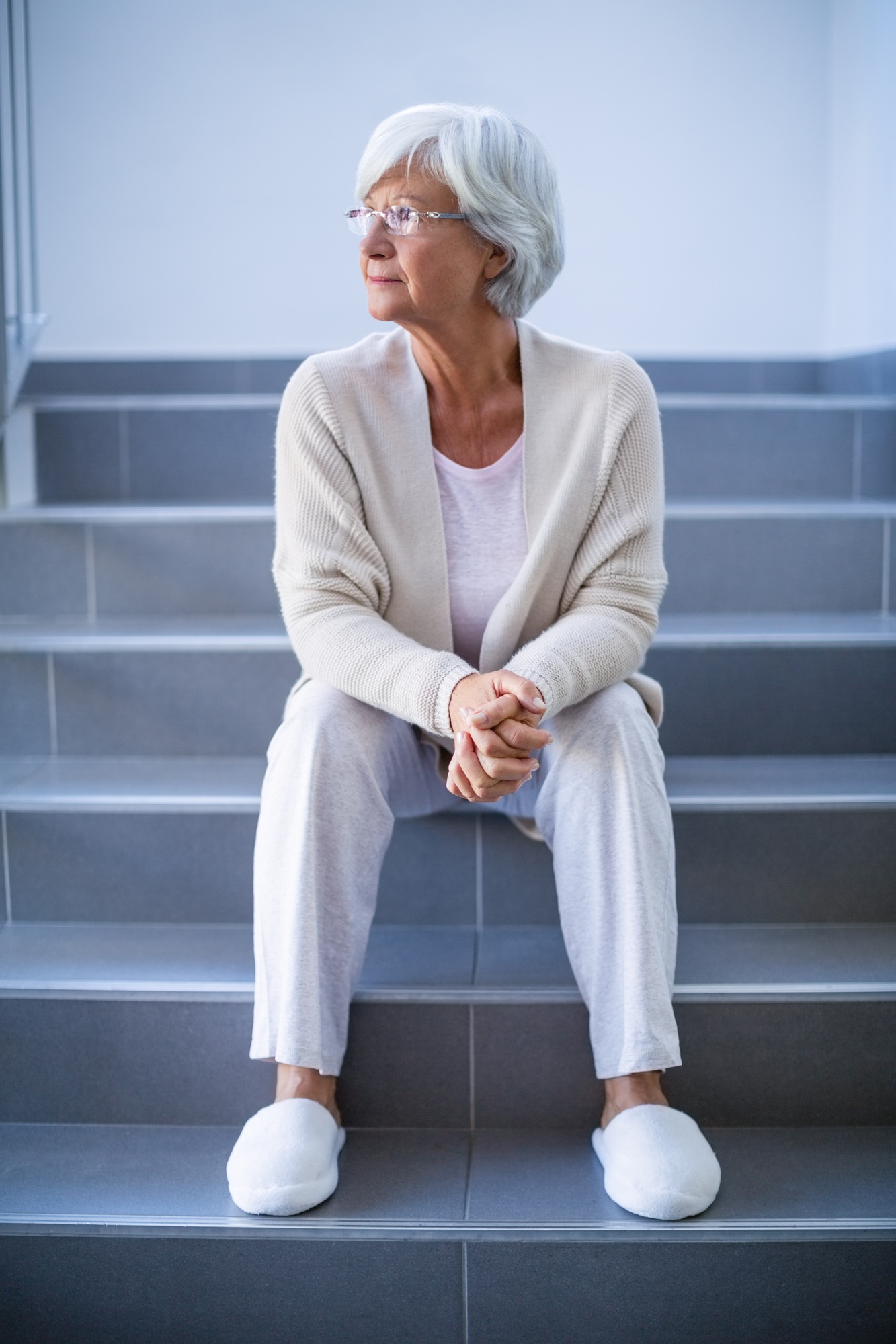 Thoughtful senior woman sitting on stairs