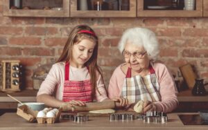 Elderly woman teaching a little girl to bake cookies