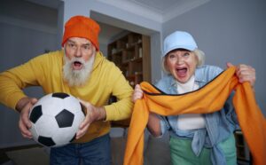 Overjoyed elderly couple watching football match on tv