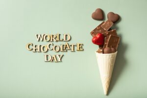 World chocolate day text with chocolate flat lay, top view on green background